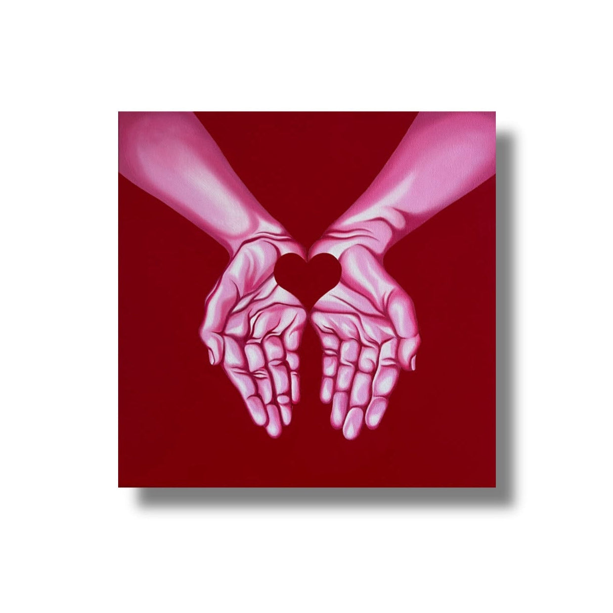 A square art print or canvas featuring two stylized hands forming a heart shape, set against a deep red background, shown on a white backdrop with a drop shadow.